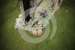 Young woman barefoot walking on the fresh, green grass in sunny summer in the morning. Restful moment. Healthy lifestyle. Brigh