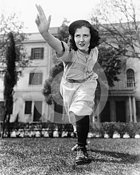 Young woman in baseball uniform throwing a ball