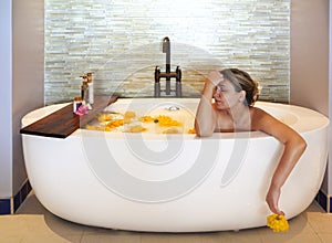 Young woman in bath with milk and flowers