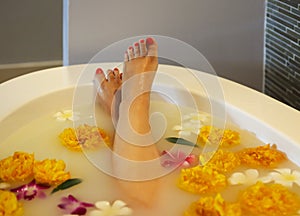 Young woman in bath with milk and flowers