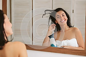 Young woman in bath towel drying hair