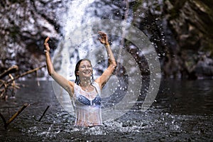 Young woman bathing in a forest pond near the waterfall.