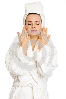Young woman in bathrobe after facial treatment
