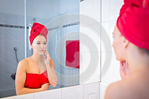 Young Woman in the Bathroom looks into a mirror