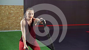 Young woman battling with ropes during cross-training workout in gym
