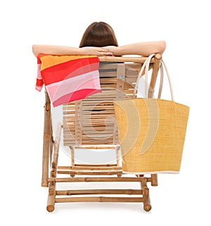 Young woman with beach accessories on sun lounger against white