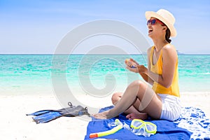 Young woman on the beach applying sun cream.