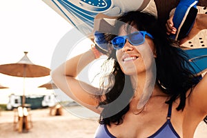 Young woman on the beach carries a surfboard on her head