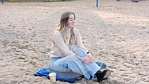 Young woman on the beach in jeans and a sweater. stress-free concept. Slow living. Enjoying the little things. Lykke