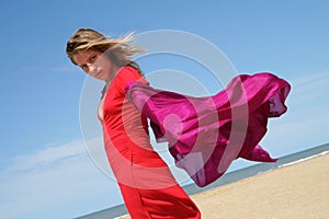Young woman on beach with red fluttering scarf