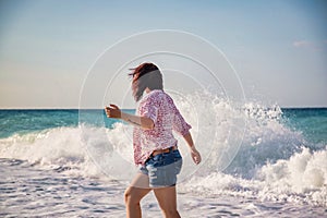 Young woman at the beach running away from the waves