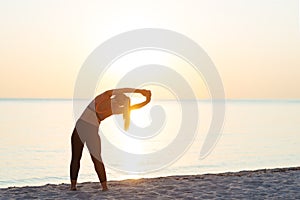 Young woman at the beach stretching after workout