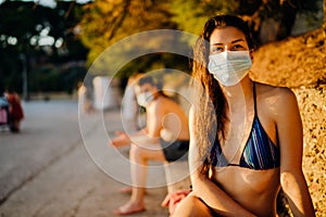 Young woman on a beach wearing a protective mask.Beach holiday vacation in the summer during coronavirus COVID-19 pandemic.Virus
