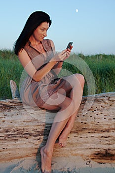 Young Woman Beachside Texting on Mobile Phone