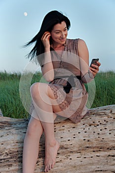 Young Woman Beachside Texting on Mobile Phone