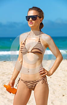 Young woman in beachwear on seacoast with sun screen