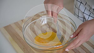 Young woman beats eggs in the kitchen. Hand mixer, beating eggs by hand.