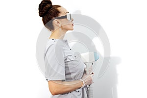 Young woman beautician in medical uniform adjusting machine for photorejuvenation or laser