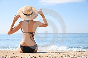 Young woman with beautiful body on sandy beach. Space for text