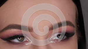 Young woman with beautiful bright evening make-up posing in studio eyes close up view
