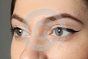 Young woman with eyebrows on grey background, closeup photo