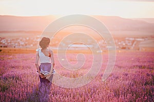 Young woman with beautiful hair standing in a lavender field at the sunset