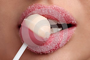 Young woman with beautiful lips covered in sugar eating lollipop, closeup