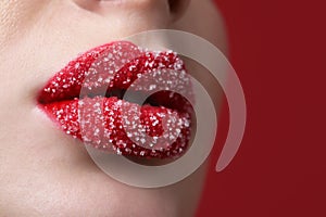 Young woman with beautiful lips covered in sugar on red background, closeup