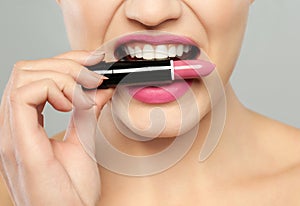 Mujer joven hermoso lápiz labial sobre el gris detallado 