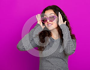 Young woman beautiful portrait, posing on purple background, long curly hair, sunglasses in heart shape, glamour concept