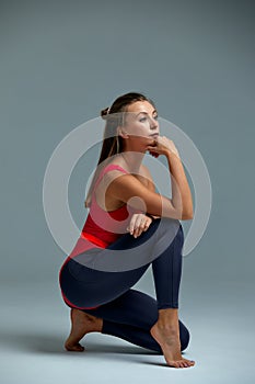 Young woman with beautiful slim healthy body posing in studio. Fitness female model in sportswear on grey background.
