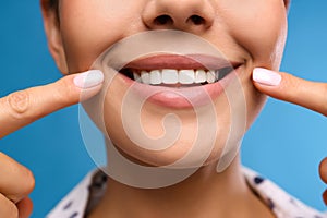 Young woman with beautiful smile on blue background, closeup. Cosmetic dentistry