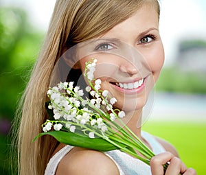 Young woman with a beautiful smile with healthy teeth with flowers. Face of a beautiful positive girl Concept on the subject