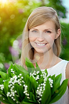 Young woman with a beautiful smile with healthy teeth with flowers. Face of a beautiful positive girl Concept on the subject