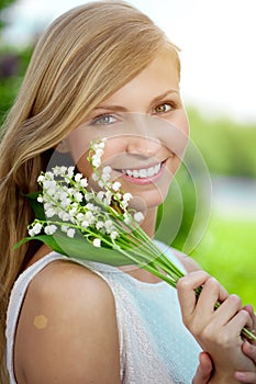 Young woman with a beautiful smile with healthy teeth with flowers. Face of a beautiful positive girl Concept on the subject