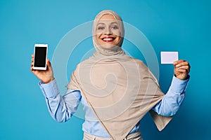 Young woman with beautiful smile holding a white blank plastic card in her hands