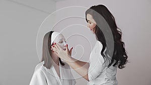 Young woman in beauty cosmetology salon with a cloth mask on face talks with female doctor dermatologist