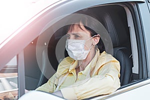 Young woman, beauty in a medical mask driving a car in town, New life in a pandemic