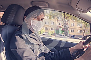 Young woman, beauty in a medical mask driving a car in town, New life in a pandemic