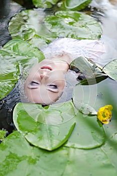 Young woman beauty portrait in water. Girl with gentle makeup in the lake among lotuses and water lilies. Outdoor