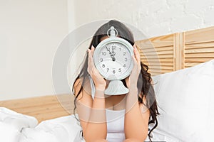 Young woman in bed at home with alarmclock