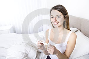 Young woman in bedroom at home wearing in white check pregnant test