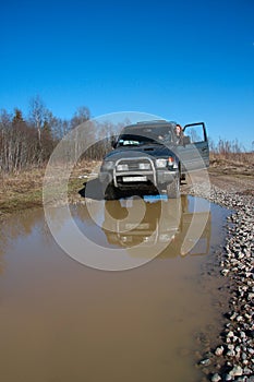 Young woman behind rudder of offroad car on dirt r