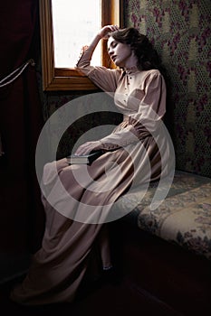 Young woman in beige vintage dress of early 20th century sleapin