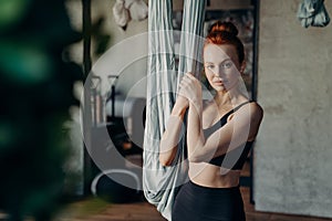 Young woman being ready for antigravity yoga exercises in studio, looking in camera