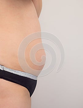 young woman with belly, overweight. side view, on white background