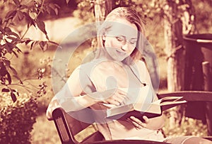 Young woman on bench reading book