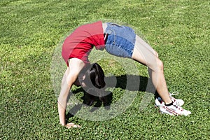 Young Woman Bending Over Backwards On Green Grass