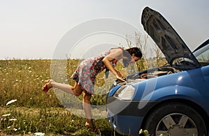 Young woman bent over a car