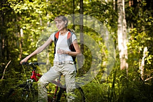 Young woman with bicycle in forest